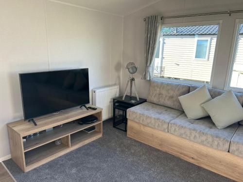 a living room with a couch and a flat screen tv at Beautiful 8 Berth Caravan With Decking At Naze Marine Holiday Park Ref 17344Br in Walton-on-the-Naze