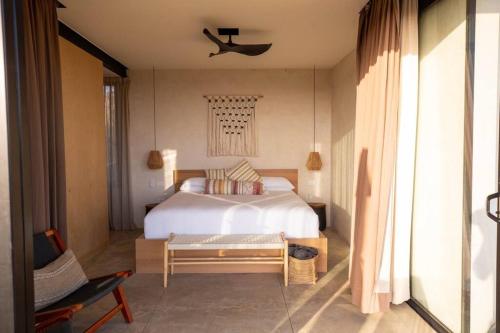 een slaapkamer met een groot wit bed en een stoel bij Nubla Residence villa Uno in Ensenada