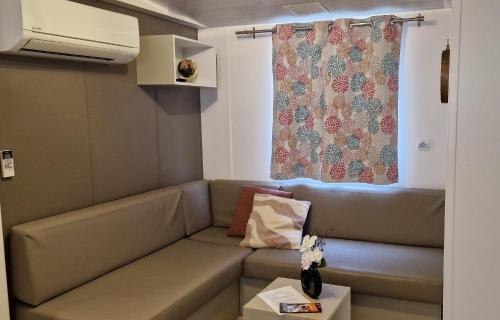 un salon avec un canapé et une fenêtre dans l'établissement Mobil-home confort 6 personnes proche Europa-Park, à Boofzheim