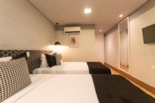 a hotel room with two beds and a tv at Hotel Heritage in Sao Paulo