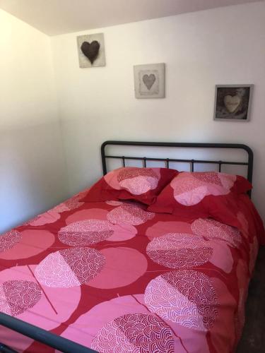 - un lit avec une couette rouge et rose et deux cœurs dans l'établissement oiseau du paradis, à Illies