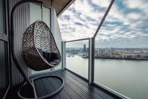 a hanging chair on a balcony with a view of the water at The Itchen River Apartments in Southampton