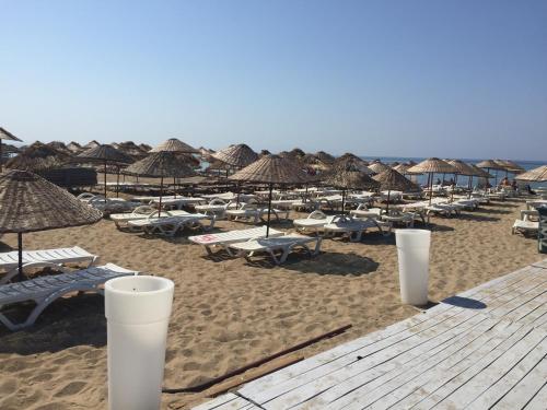 a beach with many umbrellas and chairs and tables at Grand Milano Hotel in Ayvalık