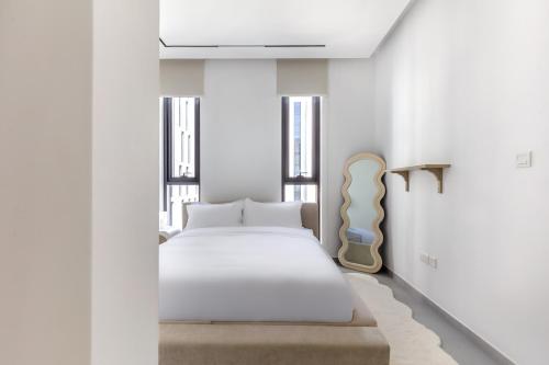 a white bedroom with a bed and windows at Sahab - Urban Living 1BR by HA in Sharjah