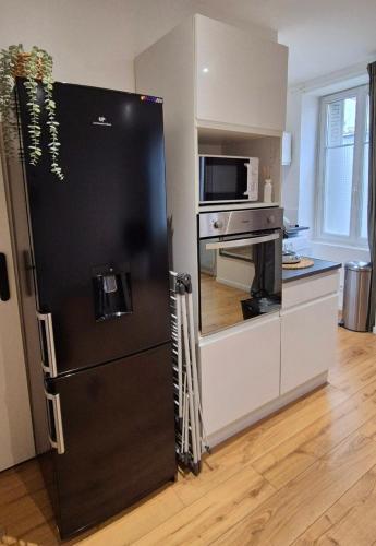 - un réfrigérateur noir dans la cuisine équipée d'un four micro-ondes dans l'établissement Studio Moderne et Cosy à Miribel, à Miribel