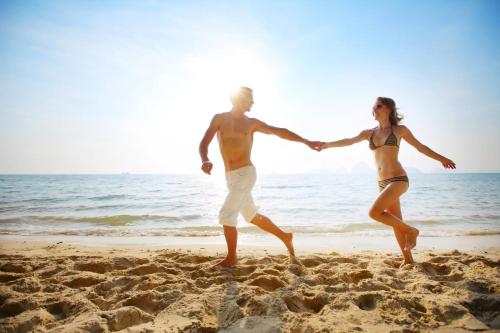 a man and a woman walking on the beach at Beautiful 8 Berth Caravan With Decking At Naze Marine Holiday Park Ref 17344Br in Walton-on-the-Naze