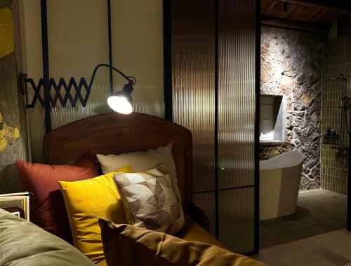 a room with a bed with a lamp and pillows at ShuShu Homestay in Jiufen