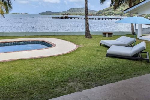 波托韦洛Entire Villa with pool in front of beach!的后院设有游泳池、椅子和遮阳伞