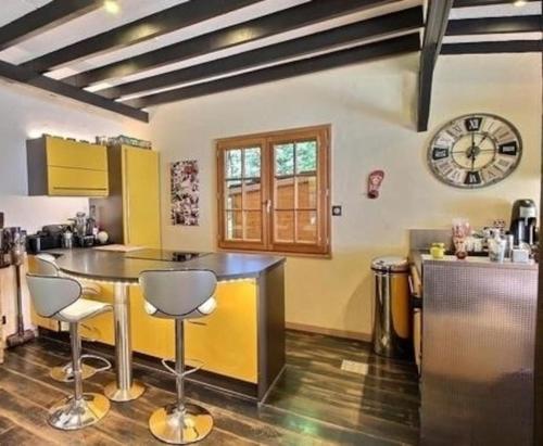 a kitchen with a counter and a clock on the wall at Chalet avec SPA et étang à proximité du Lac in Anthy