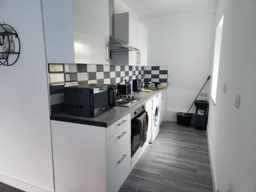 a kitchen with white cabinets and black and white tiles at Centre Apartment - Sleeps 2 & Roof Top Hot Tub in Derby