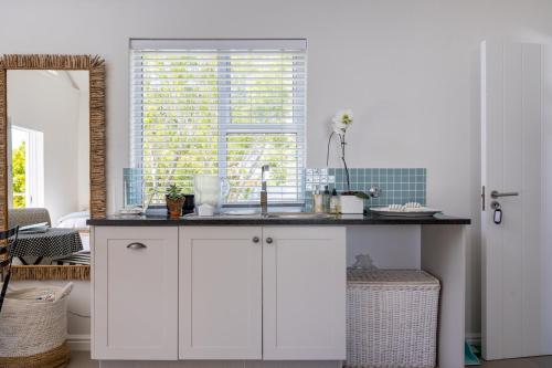 una cocina con fregadero y ventana en Stableford Beachhouse Top Apartment, en Plettenberg Bay