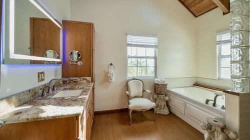a bathroom with two sinks and a tub and a chair at Carefree on Cudjoe by Last Key Realty in Cudjoe Key