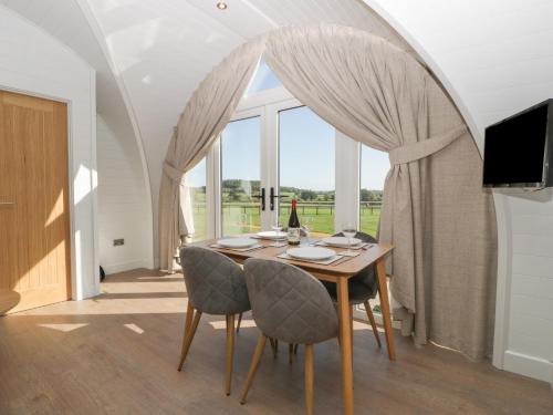a dining room with a table and chairs and a large window at Leadon View Oak in Newent