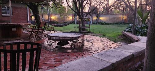 a patio with a table and chairs and a hammock at Serendipity Guesthouse in Bloemfontein
