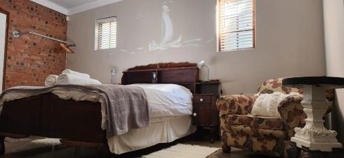 a bedroom with a bed and a chair in it at Serendipity Guesthouse in Bloemfontein
