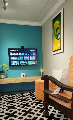 a living room with a couch and a tv on the wall at Serendipity Guesthouse in Bloemfontein
