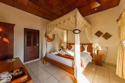 a bedroom with a bed with a canopy at Rama Shinta Hotel Candidasa in Candidasa