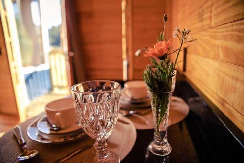 a table with two glasses and a vase with flowers at Blue Sunset in Urubici