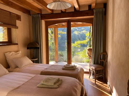une chambre avec deux lits et une grande fenêtre dans l'établissement Private Estate with 3 Lake Houses, Sauna & Hot-tub, à Castelnau-de-Mandailles