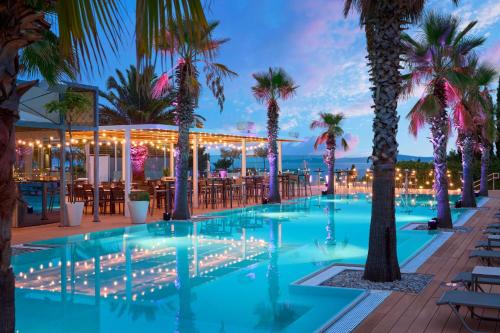 a pool with palm trees and a bar at Radisson Blu Resort & Spa in Split