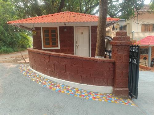 a small house with a brick wall and a sidewalk at Shantadurga Beachside Homestay in Guhagar