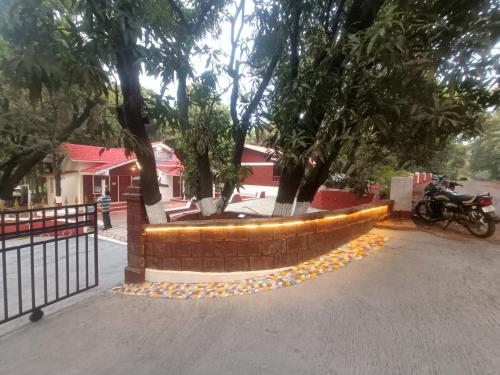 a brick retaining wall with trees and a motorcycle at Shantadurga Beachside Homestay in Guhagar