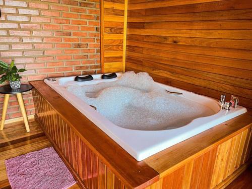 a large bath tub in a room with a brick wall at Chalé dos Coqueiros em Nova Petrópolis in Nova Petrópolis