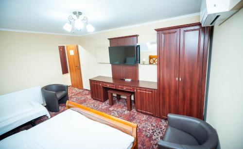a room with a bed and a desk with a tv at Dinasty Hotel in Sîntana