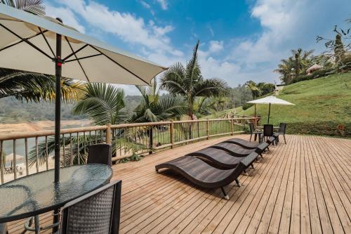 a wooden deck with chairs and tables and an umbrella at Hotel Pietrasanta in Guatapé