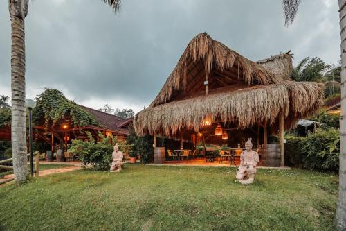 a resort with a thatched roof and statues in the yard at Hotel Pietrasanta in Guatapé