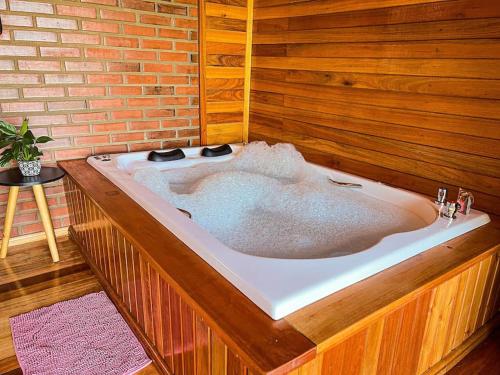 a large bath tub in a room with a brick wall at Chalé dos Coqueiros em Nova Petrópolis in Nova Petrópolis