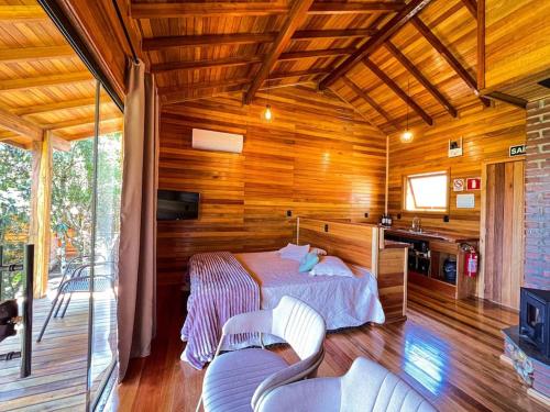 a bedroom with a bed in a wooden house at Chalé dos Coqueiros em Nova Petrópolis in Nova Petrópolis