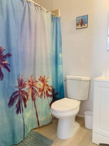 a bathroom with a toilet and a palm tree shower curtain at Coastal Cabana in Hollywood