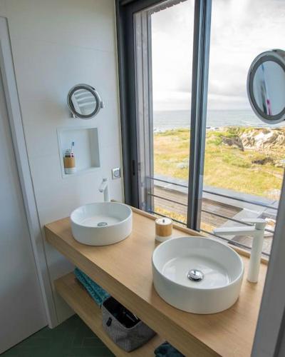 une salle de bain avec un lavabo et une grande fenêtre dans l'établissement Villa unique face océan et plage de la govelle, à Batz-sur-Mer