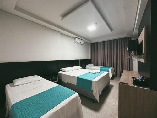 a hotel room with two beds and a television at Raf Hotel in Umuarama