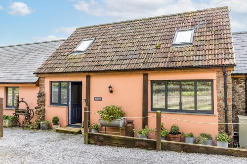 a pink house with plants in pots in front of it at The Hayloft in Tiverton
