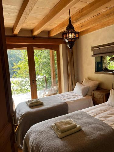 une chambre avec deux lits et une grande fenêtre dans l'établissement Lake House II // Alauzet Ecolodge + Nature spa, à Castelnau-de-Mandailles
