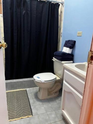 a bathroom with a toilet and a black shower curtain at Crash & Go - Hotel Style Room in San Felipe