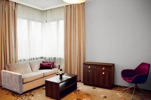a living room with a couch and a red chair at Hotel Szafran in Czeladź