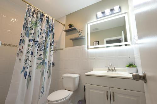 a bathroom with a toilet and a sink and a mirror at Walk to Stadium - 3BR King Bed Haven - Parking in Miami Gardens