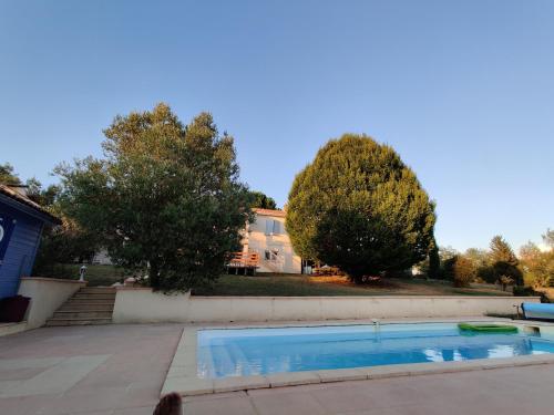 a swimming pool in a yard with trees and a house at Maison à 6 km de Eymet piscine chauffée. in Roumagne