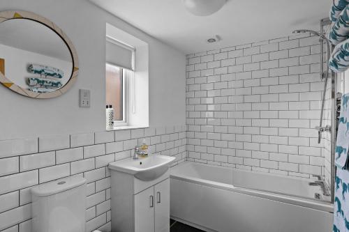 a bathroom with a tub and a sink and a mirror at The Hayloft in Tiverton