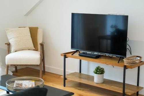 a television sitting on a table next to a chair at SUNRISE 1 Bedroom Apartment in Central Eastbourne in Eastbourne