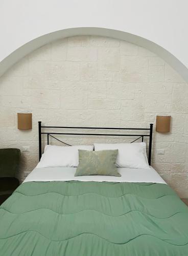 a bedroom with a bed with a green blanket at La casa di Babele in Martina Franca