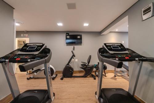 a gym with three treadmills and three elliptical machines at Hotel Heritage in Sao Paulo