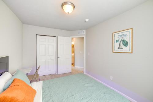 a bedroom with white walls and a bed with an orange pillow at 10 Mi to Grand Rapids Modern Townhome! in Kentwood