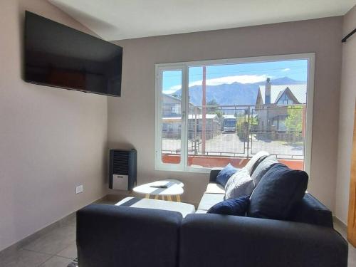 een woonkamer met een bank en een groot raam bij Moderno Duplex 1 - Complejo Las Cerezas in Esquel