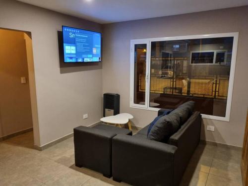 een woonkamer met een bank en een flatscreen-tv bij Moderno Duplex 1 - Complejo Las Cerezas in Esquel