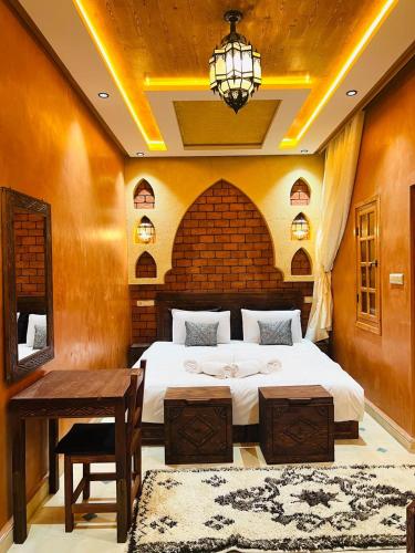 a bedroom with a bed and a table and a chandelier at Dar Chams Ouarzazate in Ouarzazate
