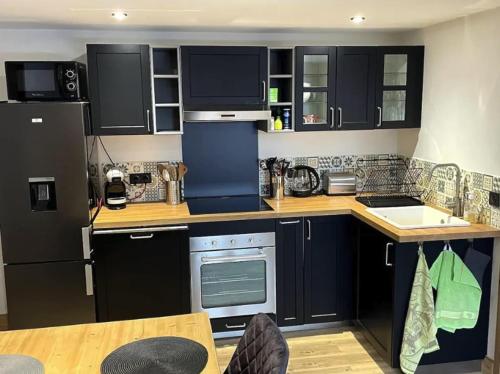 - une cuisine avec des armoires noires et un réfrigérateur dans l'établissement Apartment Belle Vue, à Les Coches